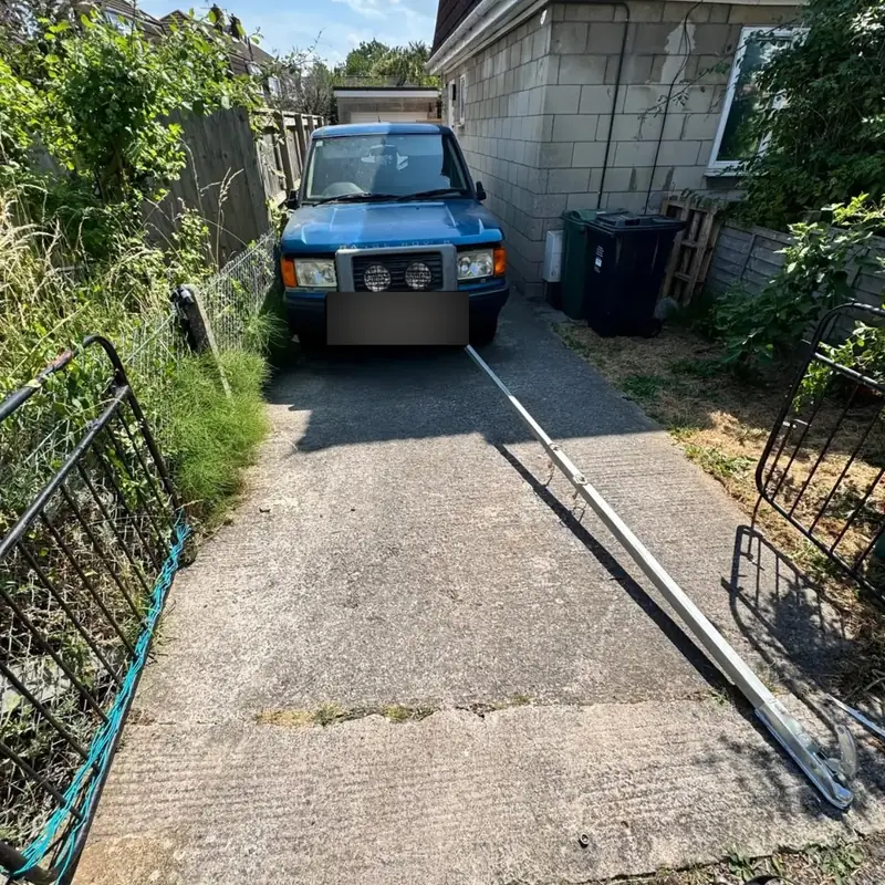 Non-running Land Rover Discovery being winched out of a narrow driveway